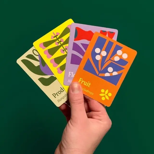 Hand holding four colorful botanical flashcards — orange card labeled "Fruit"