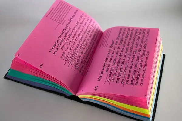Open book with neon-pink pages and rainbow edge-dyed sections