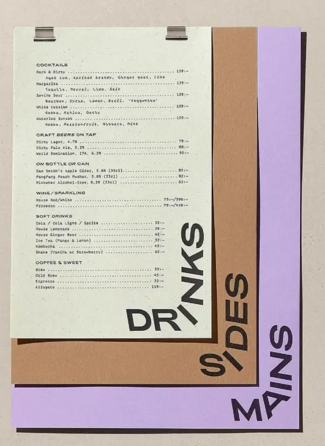 Layered paper restaurant menu with vertical DRINKS / SIDES / MAINS labels