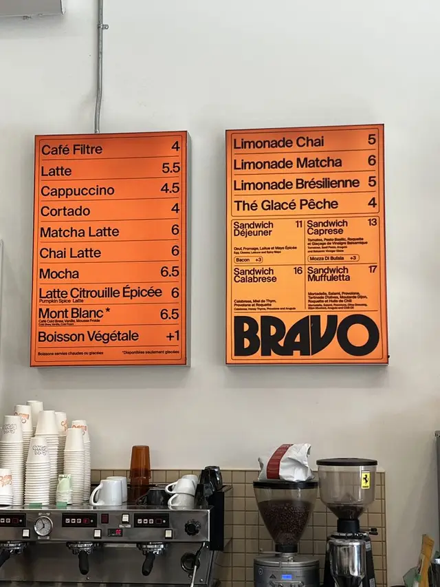Orange framed cafe menu boards with BRAVO logo over espresso machine
