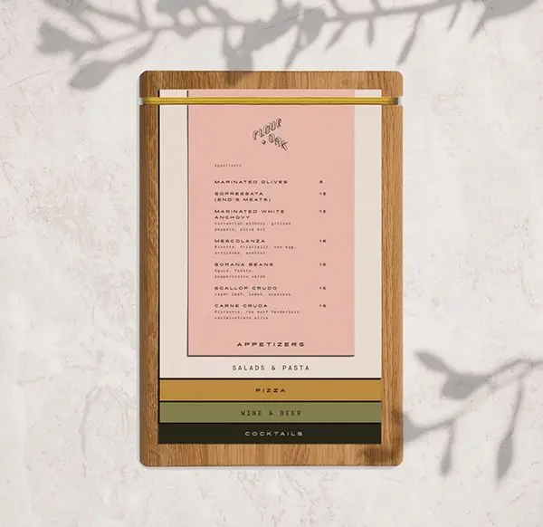 Pink restaurant menu on oak clipboard with stacked color bars, marble tabletop