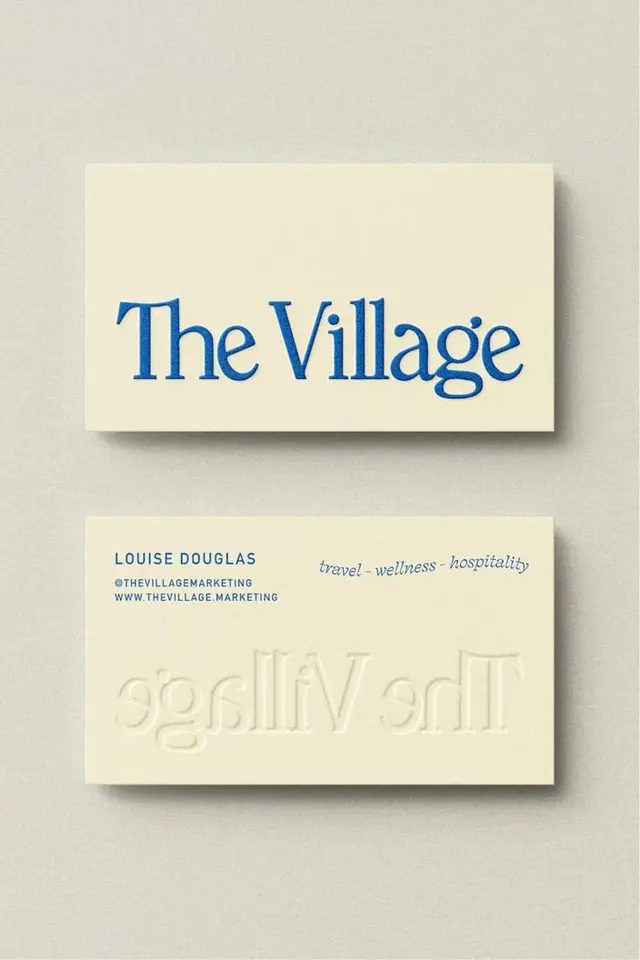 The Village — cream letterpress business card with blue serif logo