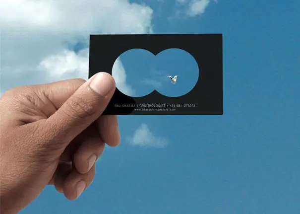 Die-cut black business card framing a bird in blue sky