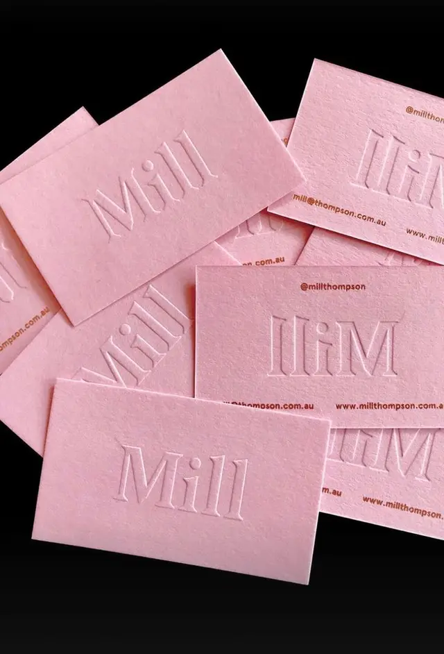 Pink blind-embossed 'Mill' business cards on black background