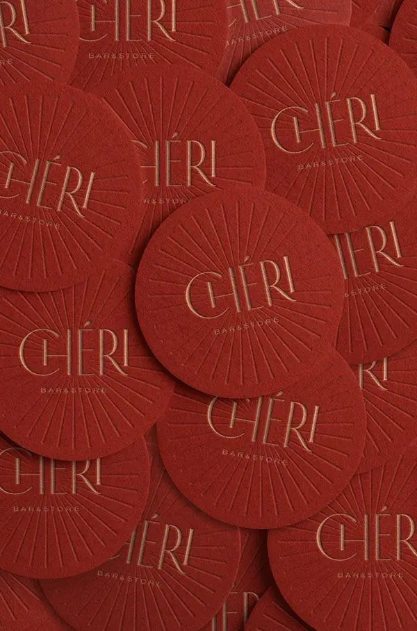 CHÉRI embossed red coasters with gold-foil logo