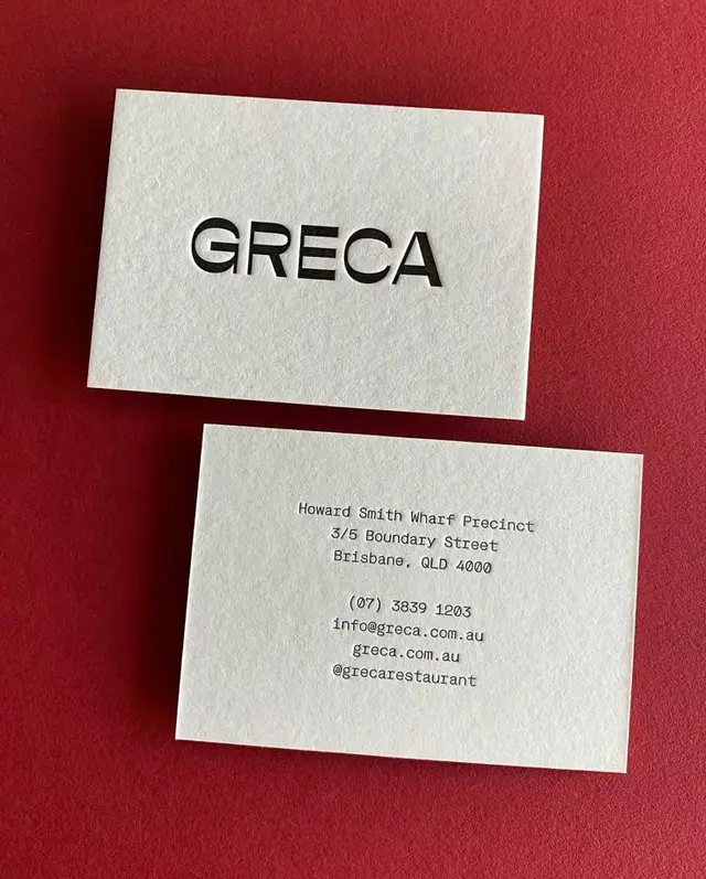 GRECA restaurant business cards — letterpress cream cards on red background