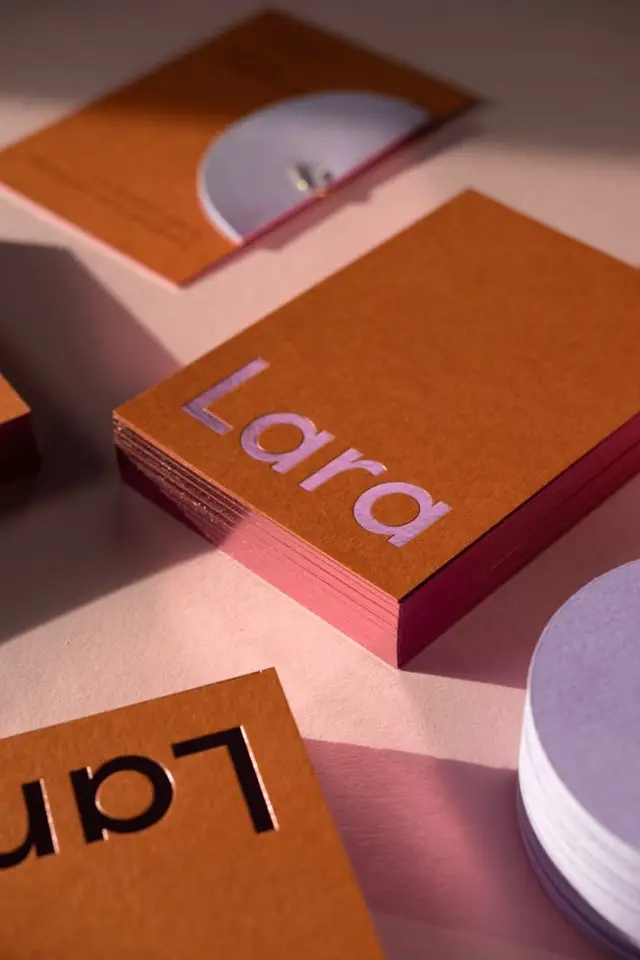 Stacked kraft business cards with pink edge and lavender 'Lara' logo