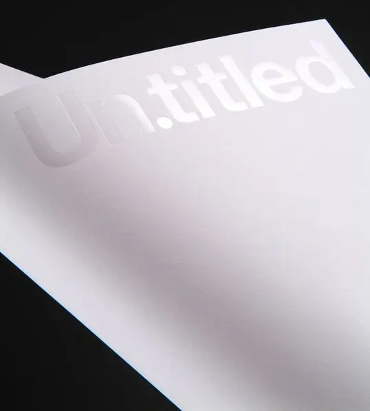 White-on-white embossed 'Un.titled' on heavy paper — close-up