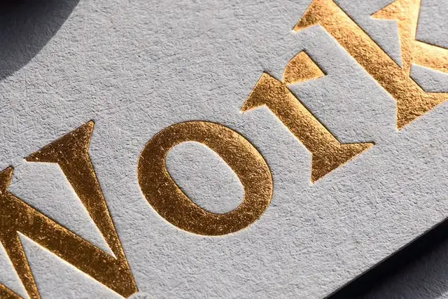 Gold foil-stamped serif typography on textured gray paper