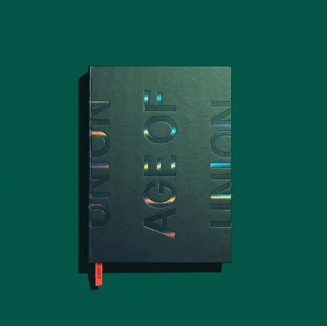 Dark green hardcover with holographic embossed typography ('AGE OF')