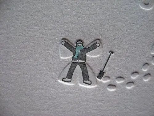 Embossed winter illustration — person making a snow angel with shovel on textured paper
