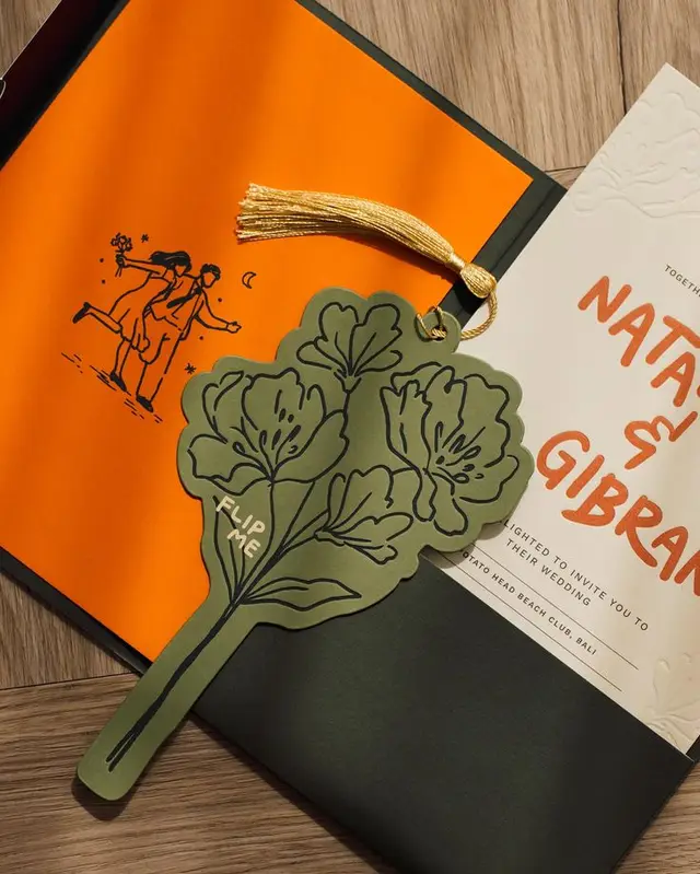 Olive die-cut floral tag with gold tassel on orange pocketfold wedding invitation