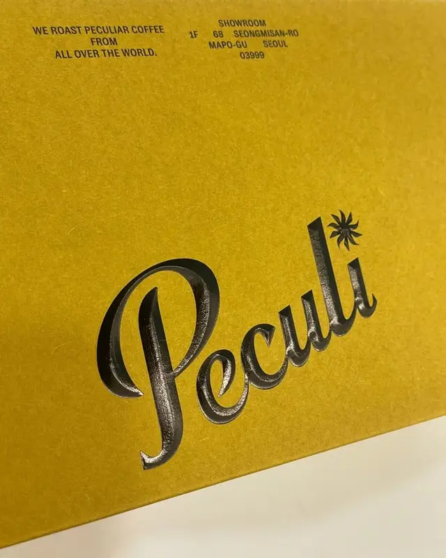 Mustard-yellow coffee packaging with embossed 'Peculi' logo