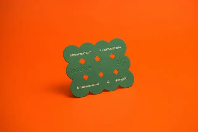 Green scalloped die-cut business card on bright orange background