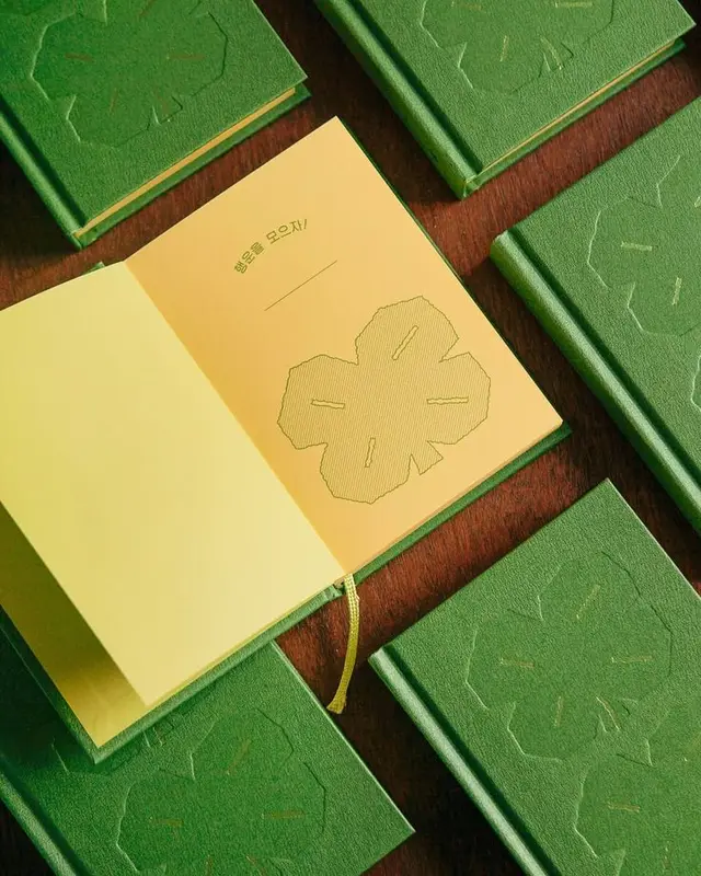 Green hardcover notebooks with embossed four‑leaf clover and yellow endpapers