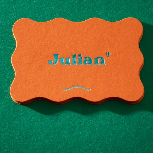 Scalloped orange letterpress name card 'Julian' on green felt