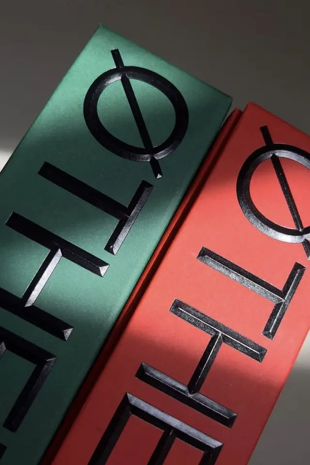 Green and red metallic packaging with black embossed geometric logotype