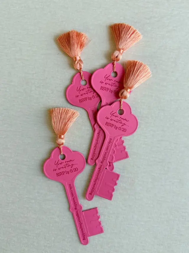 Hot‑pink key-shaped RSVP tags with peach tassels