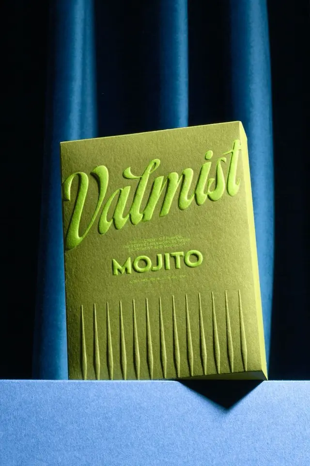 Lime-green embossed 'MOJITO' packaging on blue velvet backdrop