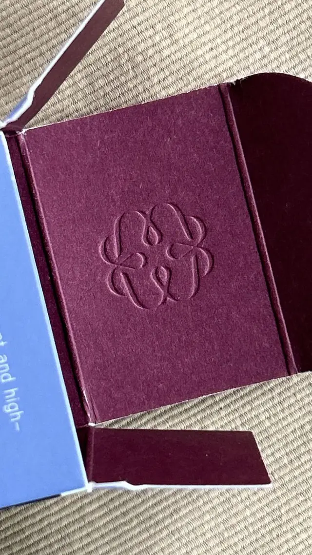 Burgundy paperboard box interior with debossed looped logo