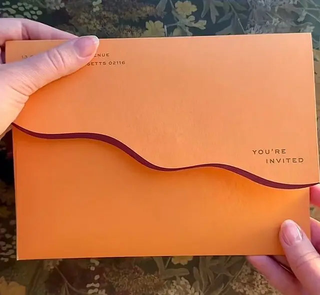 Orange die-cut invitation envelope with wavy purple liner
