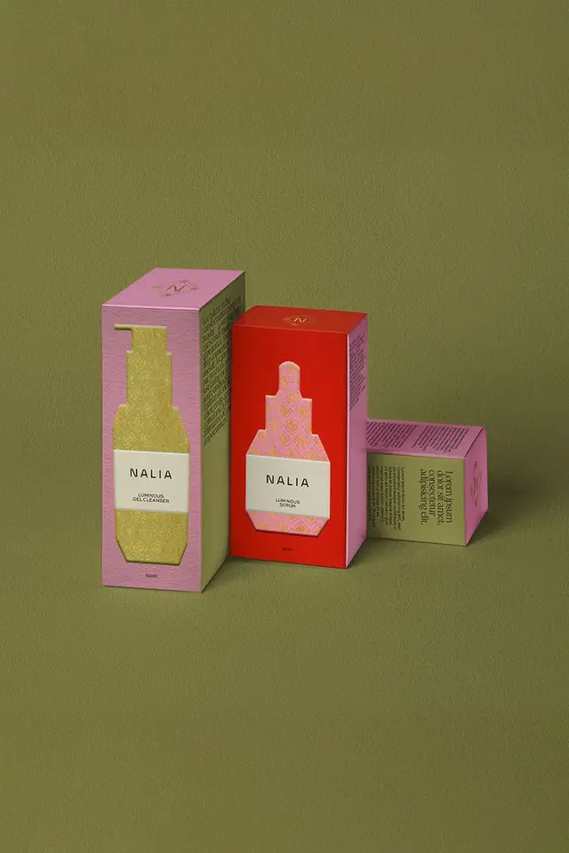 NALIA luminous skincare packaging — pink and red paperboard boxes on olive backdrop