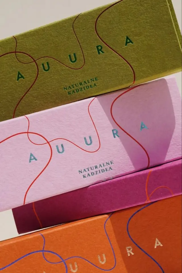 AURA natural incense packaging — stacked textured boxes in olive, pink, magenta, orange