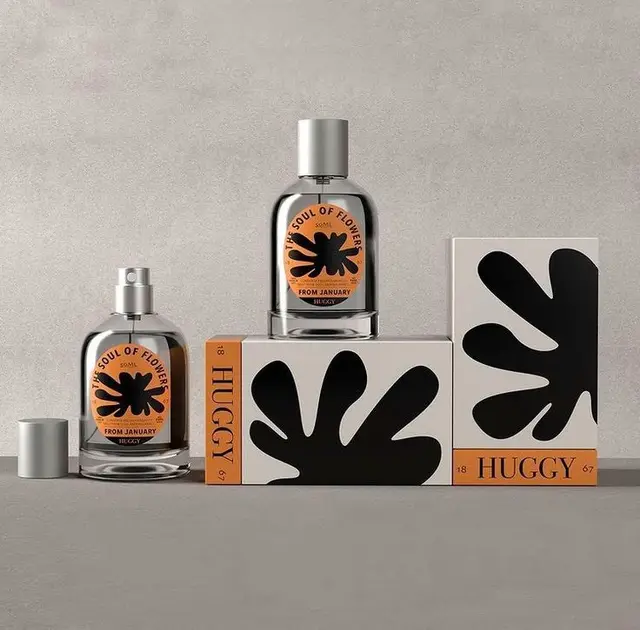 HUGGY perfume packaging — glass bottles with black abstract floral motif and orange labels