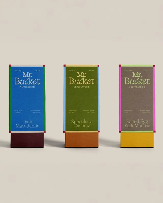 Mr. Bucket Chocolaterie — three color‑blocked chocolate boxes (Dark Macadamia, Speculoos C