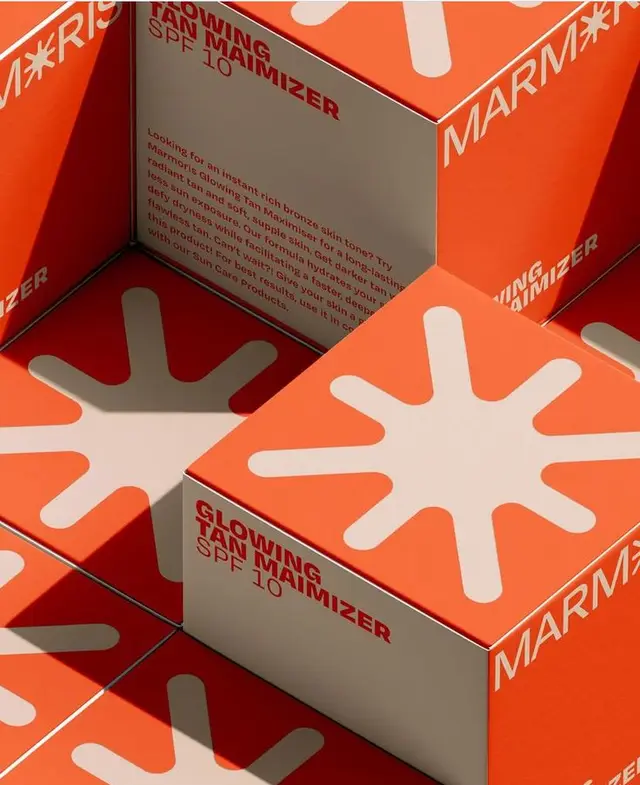 Orange sunburst cosmetic boxes — "Glowing Tan Maimizer SPF 10" packaging