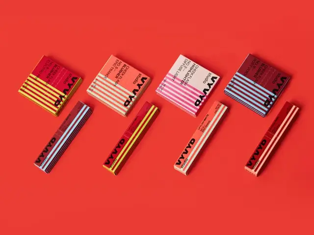 Striped cosmetic tubes and matching square boxes on red backdrop