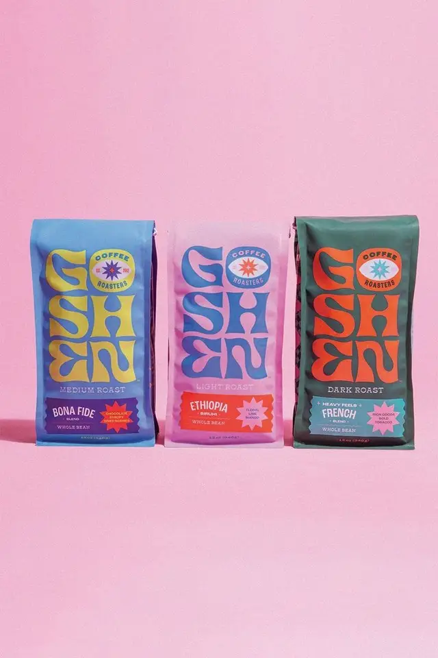 Three colorful whole‑bean coffee bags with retro typography on pastel pink backdrop