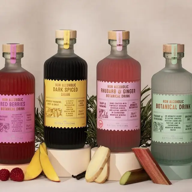 Studio photo — four frosted-glass non-alcoholic botanical drinks with pastel labels