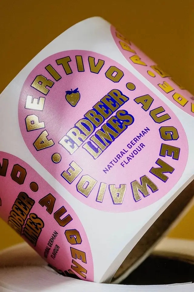 Roll of pink circular 'ERDBEER LIMES' product labels with gold lettering