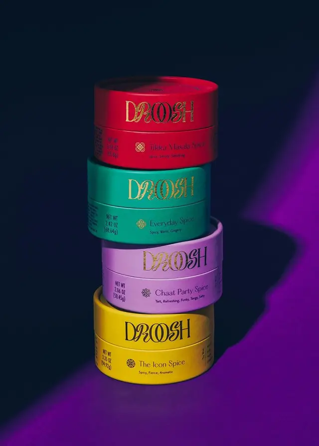 Stacked DROSH spice tins — red, teal, lavender and yellow with gold foil logo