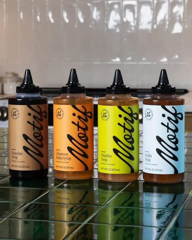 Four flavored syrup squeeze bottles on green tiled counter