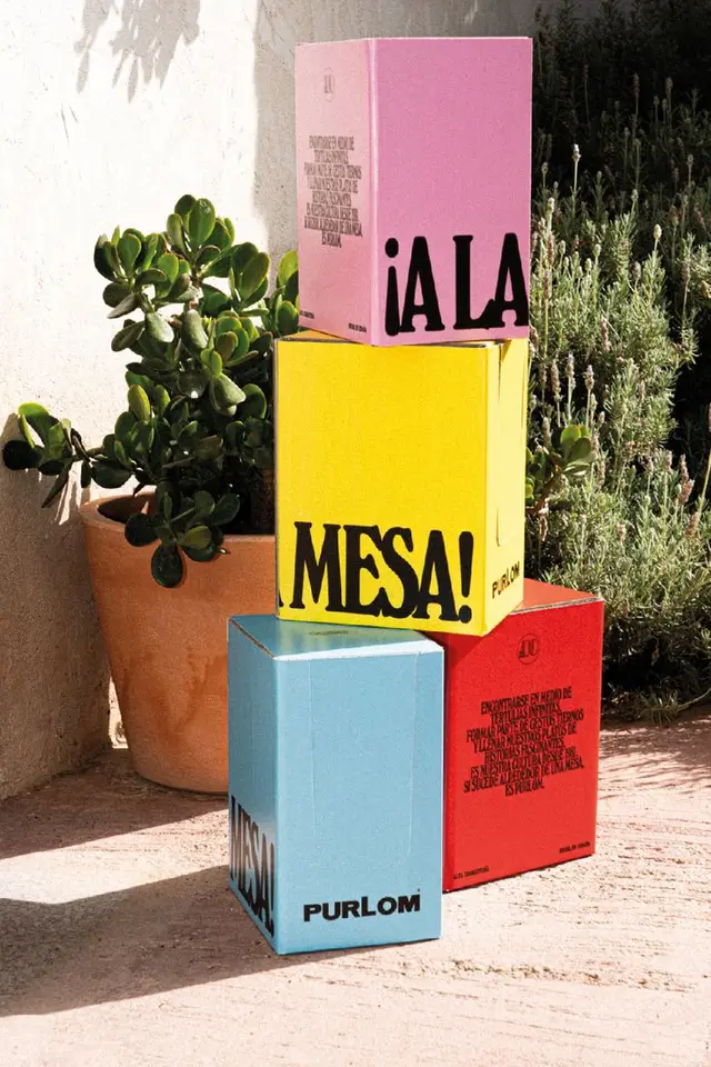 Color-block stacked PURLOM packaging with bold black typography on sunlit patio