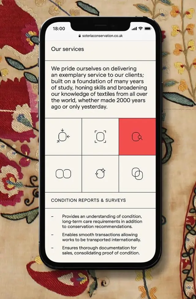 Mobile UI mockup of Soteria Conservation services page on smartphone over embroidered silk