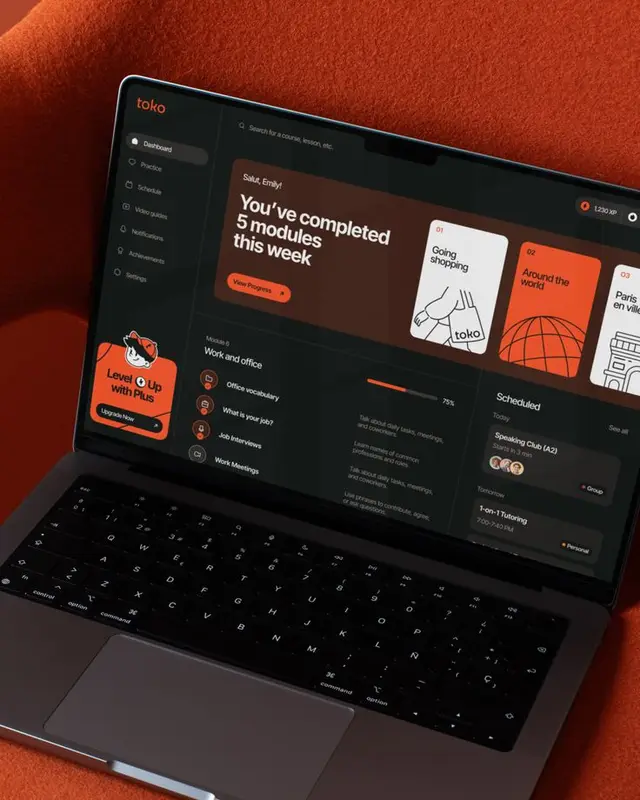 toko dark‑mode learning dashboard on laptop with orange fabric background