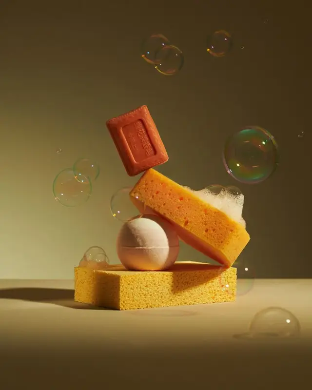 Stacked yellow sponges, peach bath bomb and embossed soap with bubbles