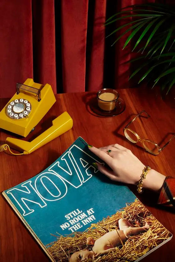 Teal NOVA magazine on wood table with mustard-yellow rotary phone