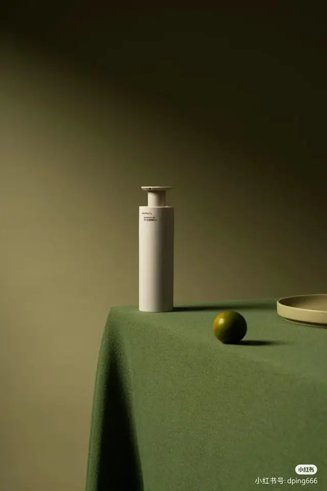 Minimalist white pump bottle on olive-green cloth with lime and ceramic plate