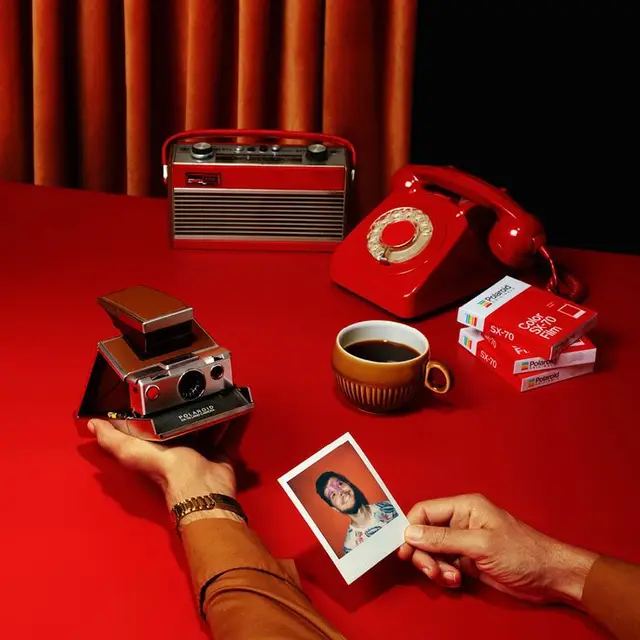 Red retro still life with Polaroid SX-70 and rotary phone