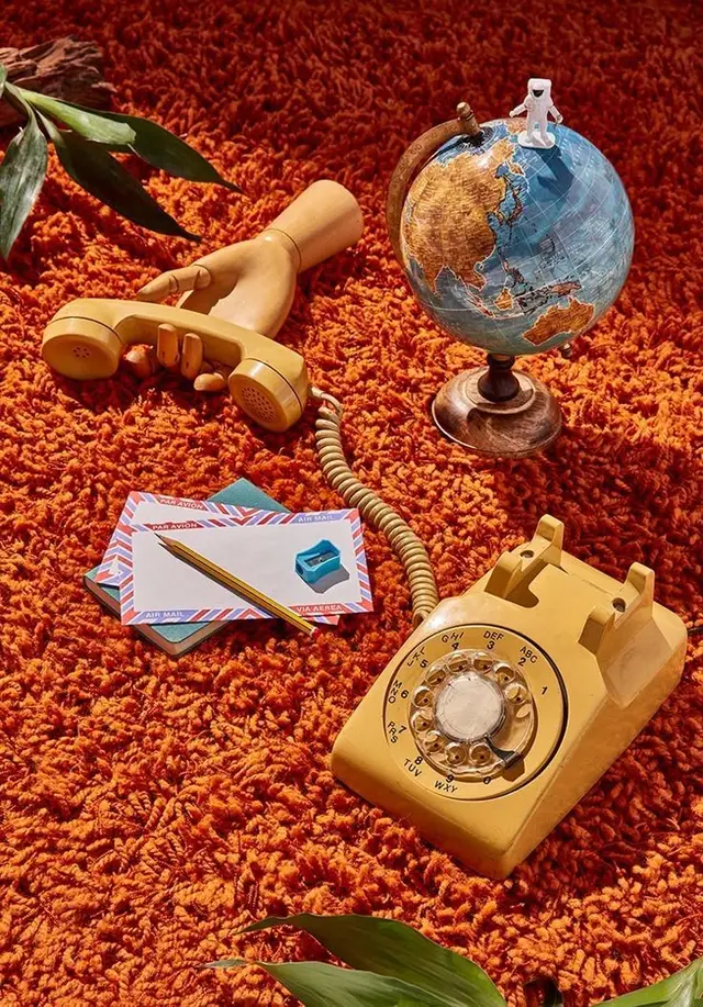 Mustard-yellow rotary phone and globe on burnt-orange shag rug