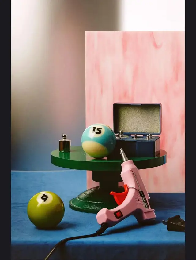 Studio still life with pool balls, pink hot glue gun, and green pedestal