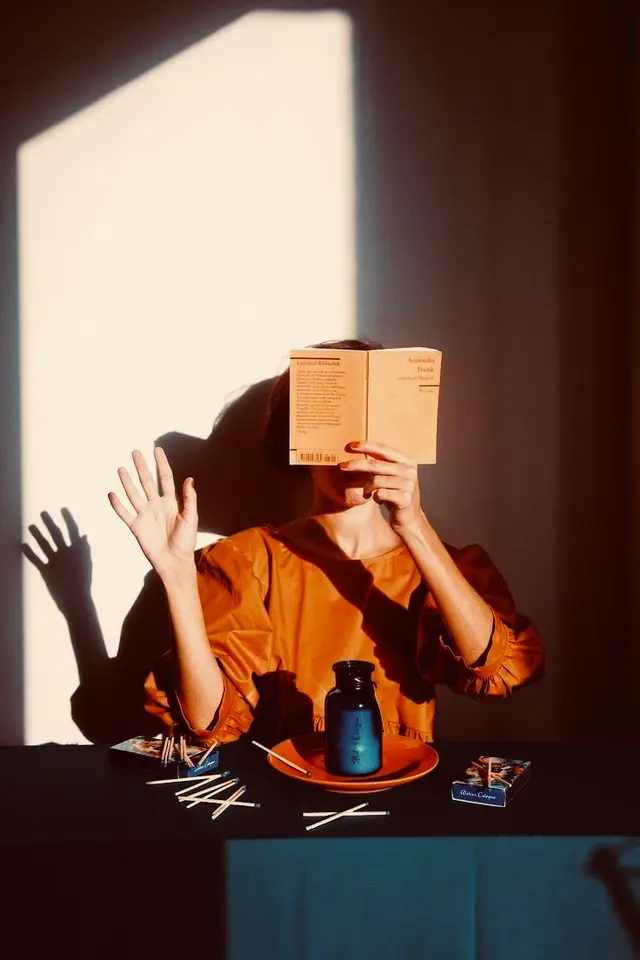 Sunlit Portrait: Reader Hides Behind Paperback with Matches