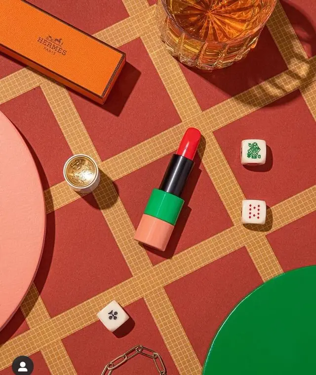 Hermès orange box with color‑block lipstick and mahjong dice — editorial flat lay