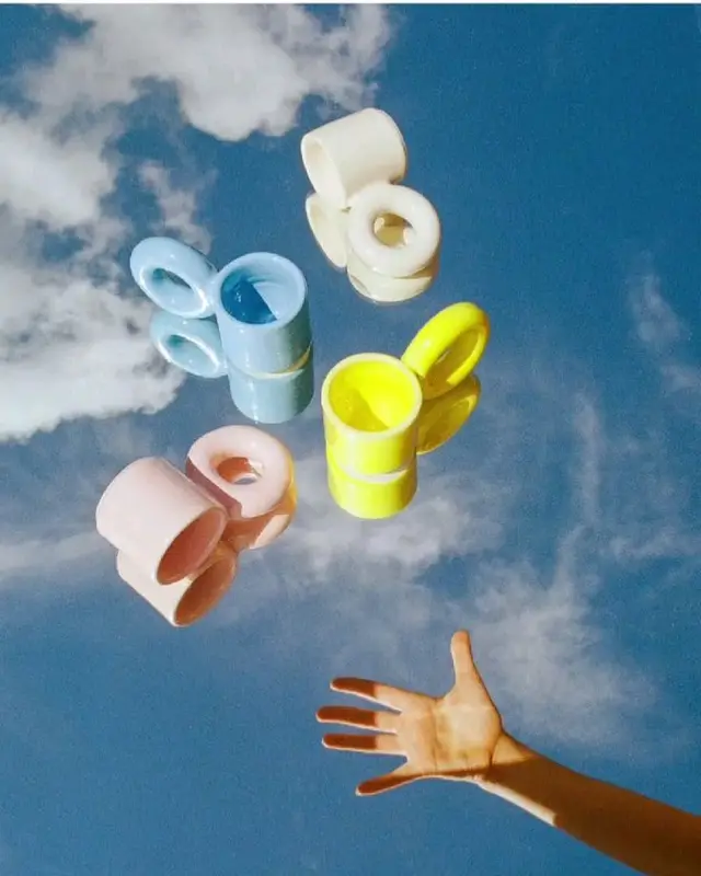 Floating pastel glazed ceramic cups over mirrored sky