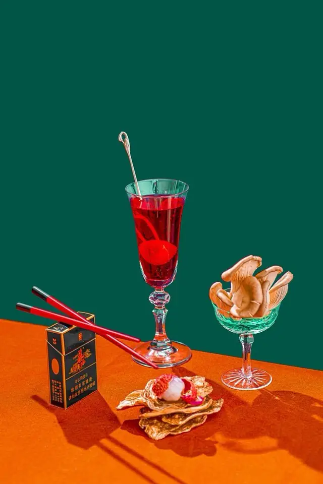 Studio still life — red cocktail, oyster mushrooms and black box on teal and orange planes