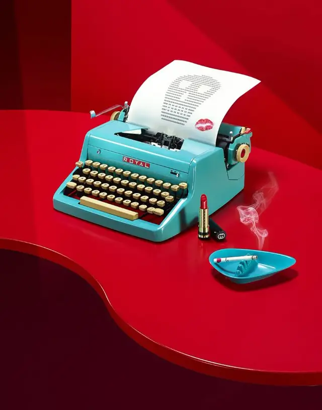 Turquoise Royal typewriter on glossy red table with lipstick and smoking ashtray